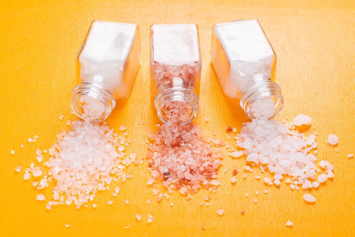 Spilled Himalayan and sea salt from glass jars, representing salt sensitivity and its impact on health
